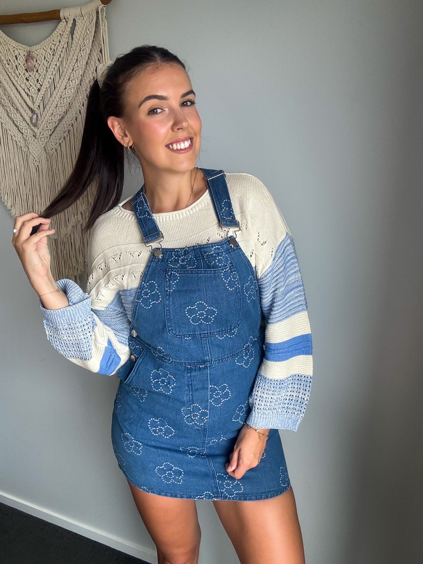 Girl wearing blue overall denim dress with flower print.