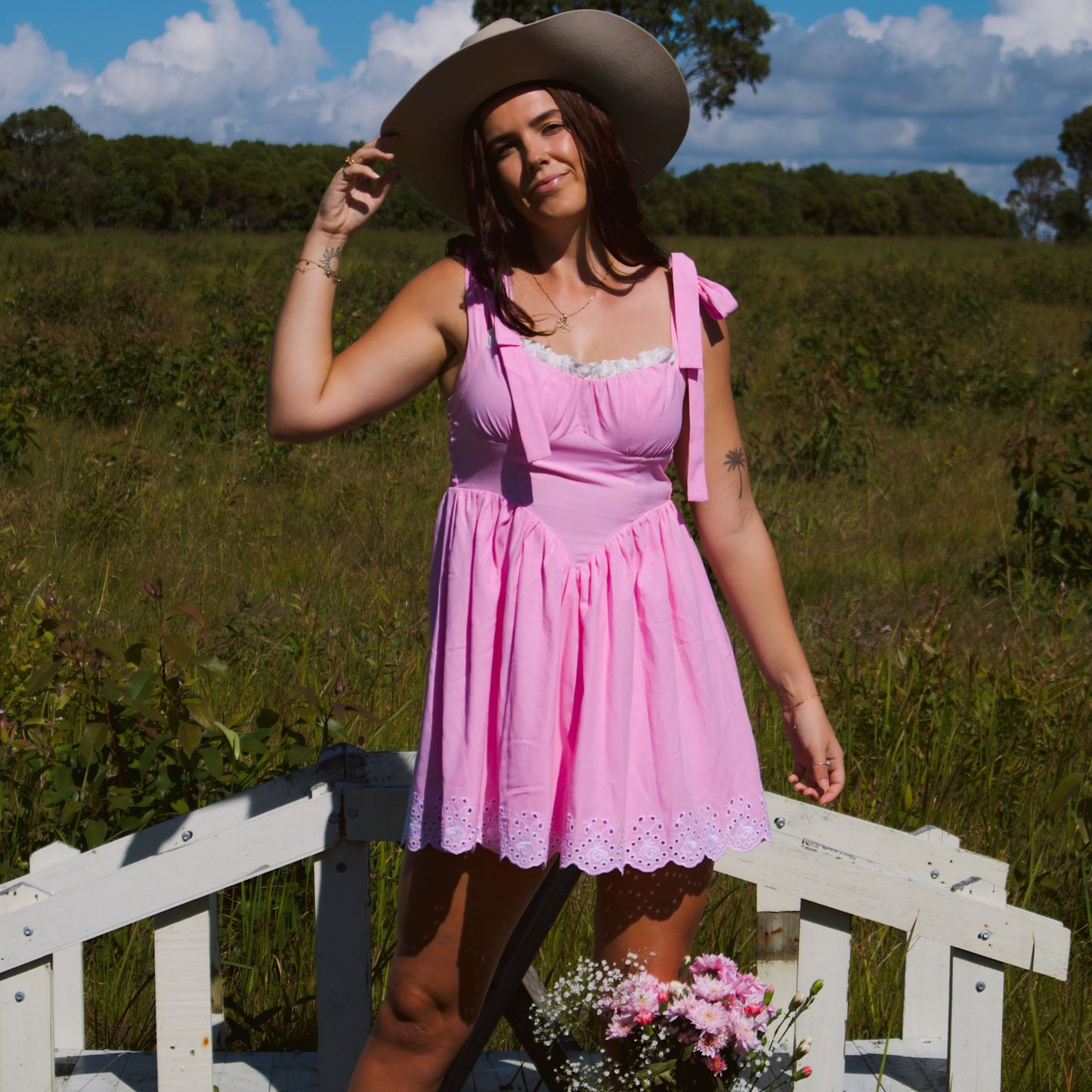 Model wearing a pink dress with adjustable straps and eyelet lace trimming at the hem, creating a sweet and feminine look