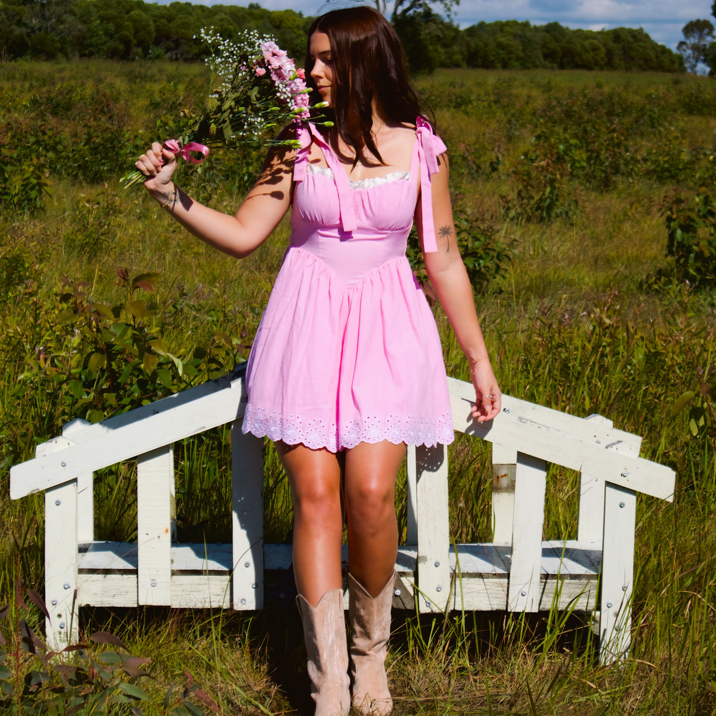 Model wearing a pink dress with adjustable straps and eyelet lace trimming at the hem, creating a sweet and feminine look.