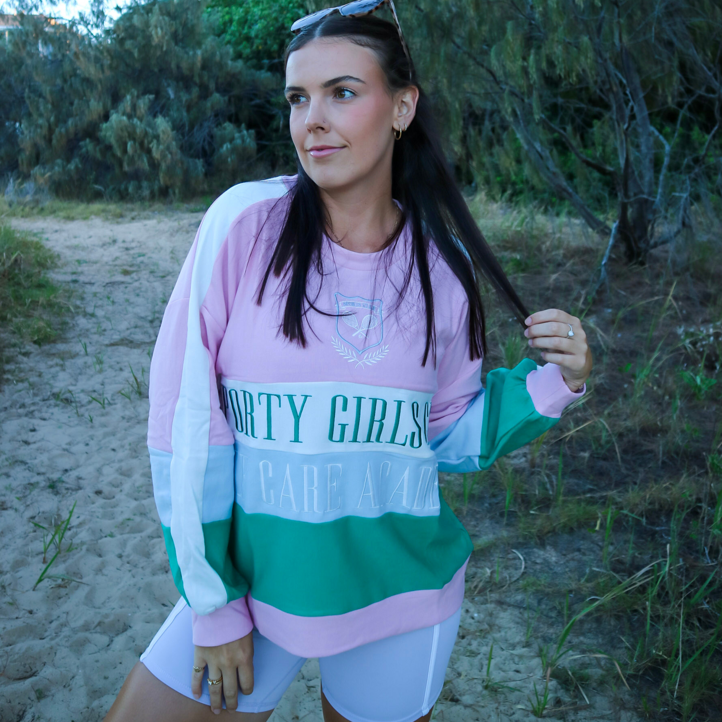 Woman wearing a colorful sweatshirt with text in an outdoor setting