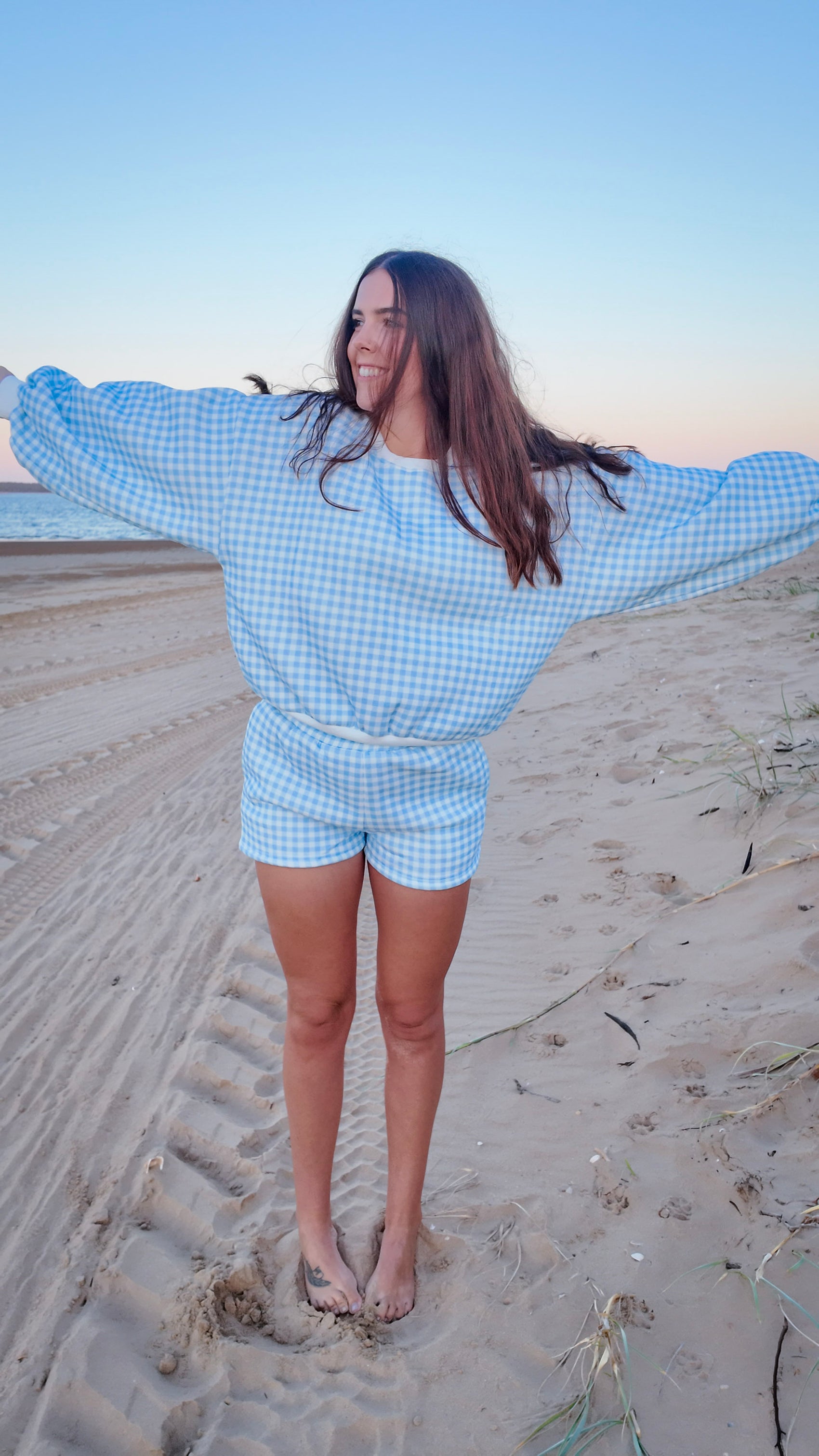 Person wearing a blue checkered outfit on a sandy beach