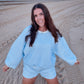 Woman in a blue checkered outfit on a sandy beach at sunset