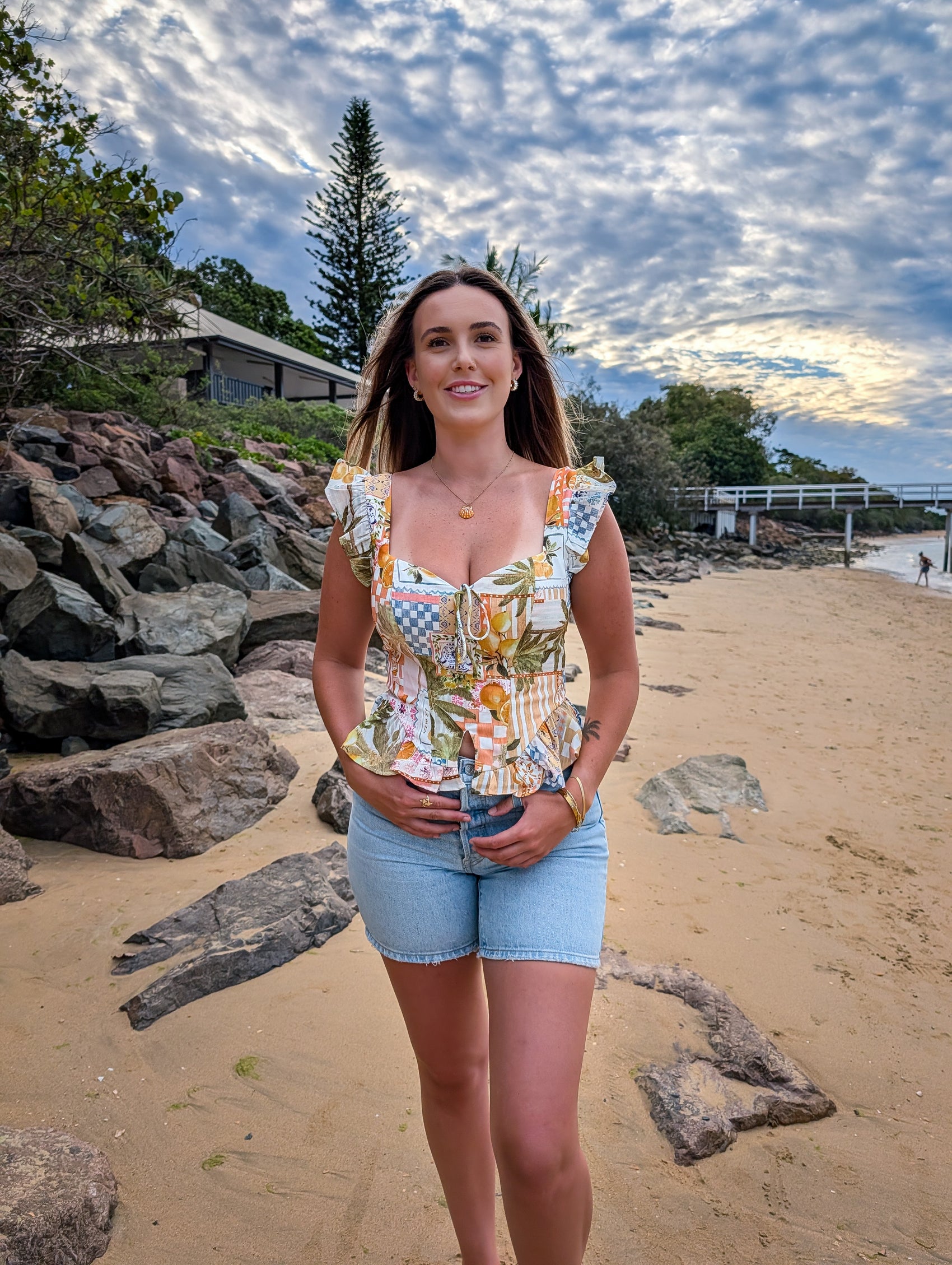Woman standing on a beach with rocks and trees in the background