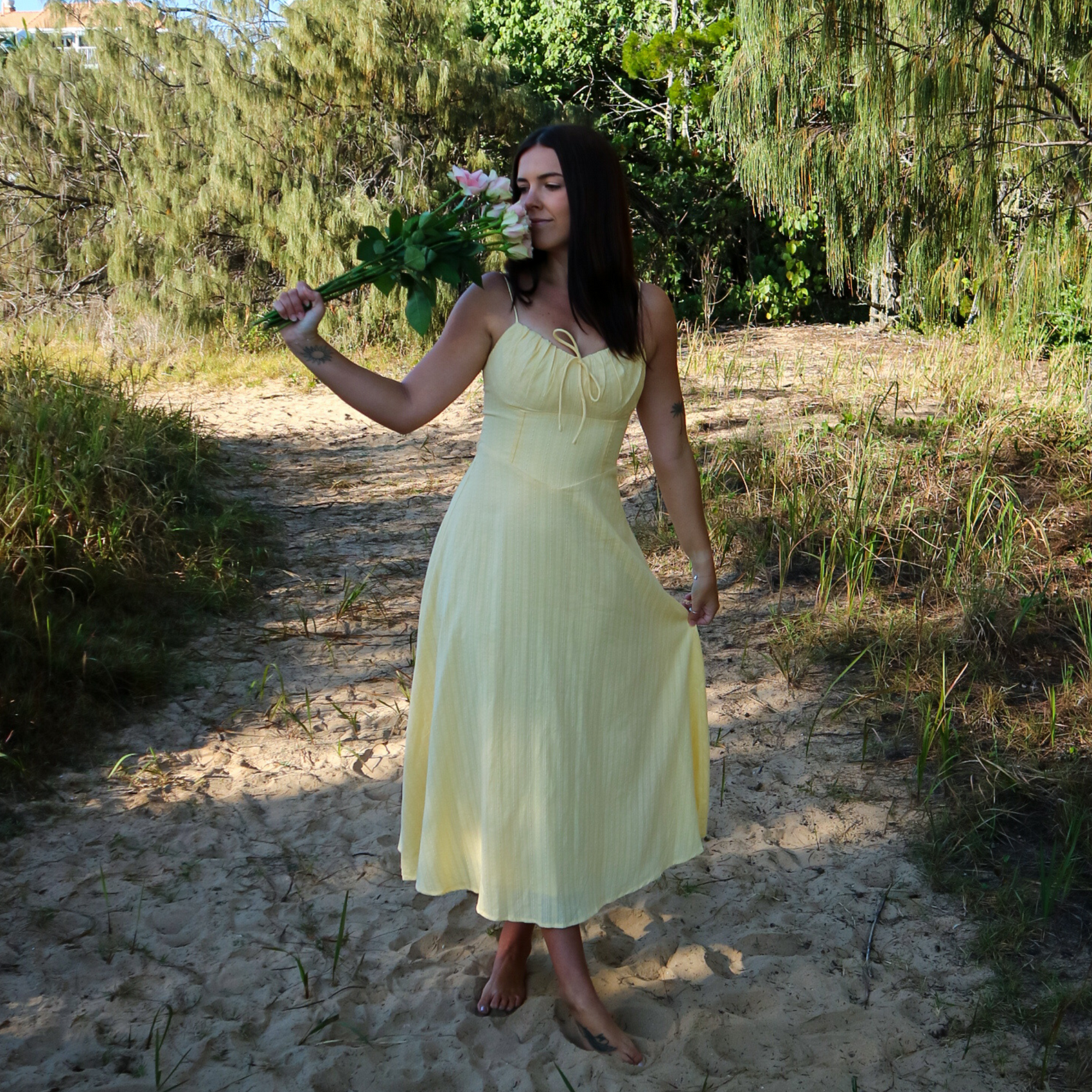 Woman in a yellow dress holding flowers in a natural setting