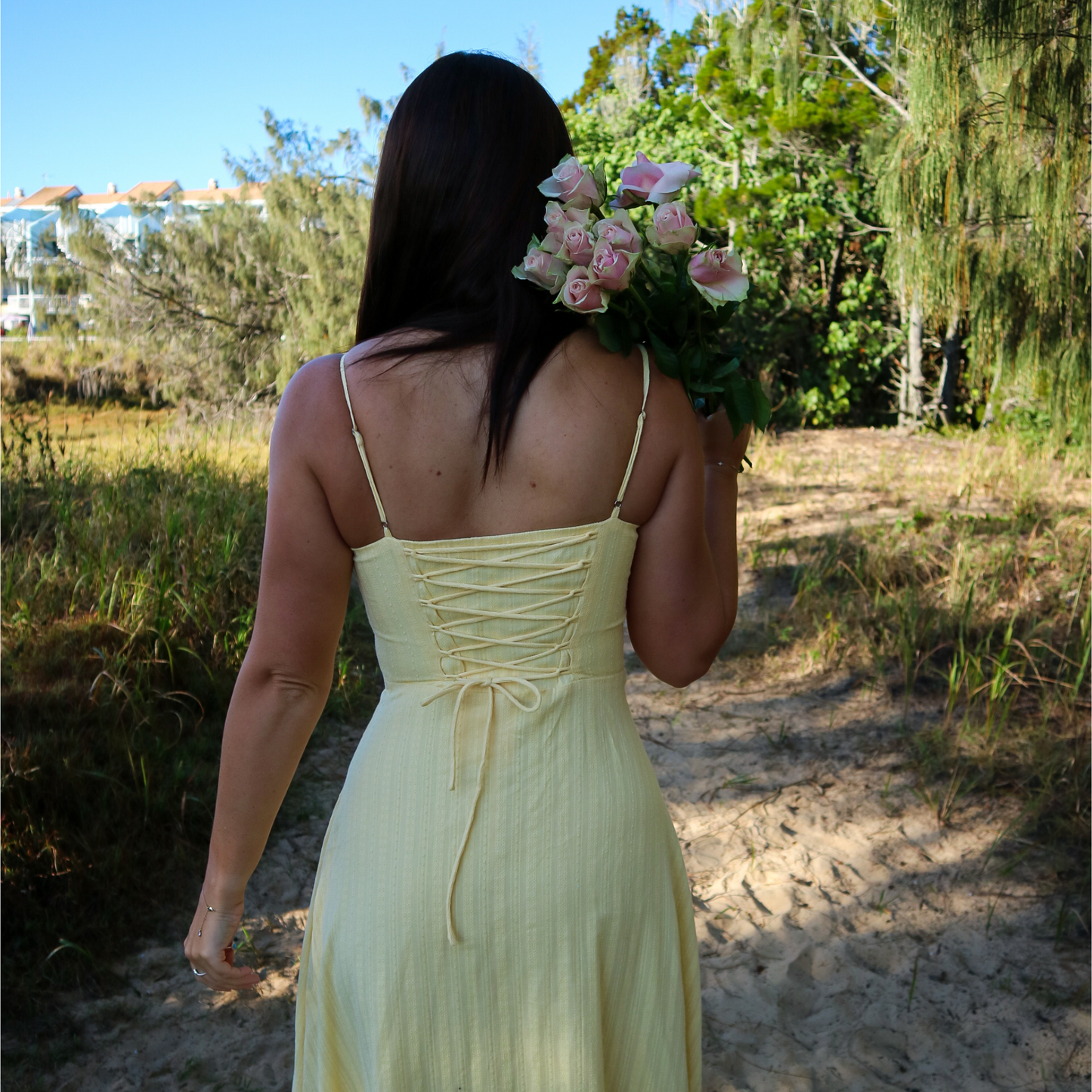 Woman in a yellow dress holding flowers in a natural setting