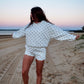 Woman in a polka dot outfit standing on a beach at sunset