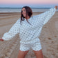 Woman in a polka dot outfit on a sandy beach at sunset