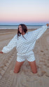 Woman in a polka dot outfit on a sandy beach at sunset