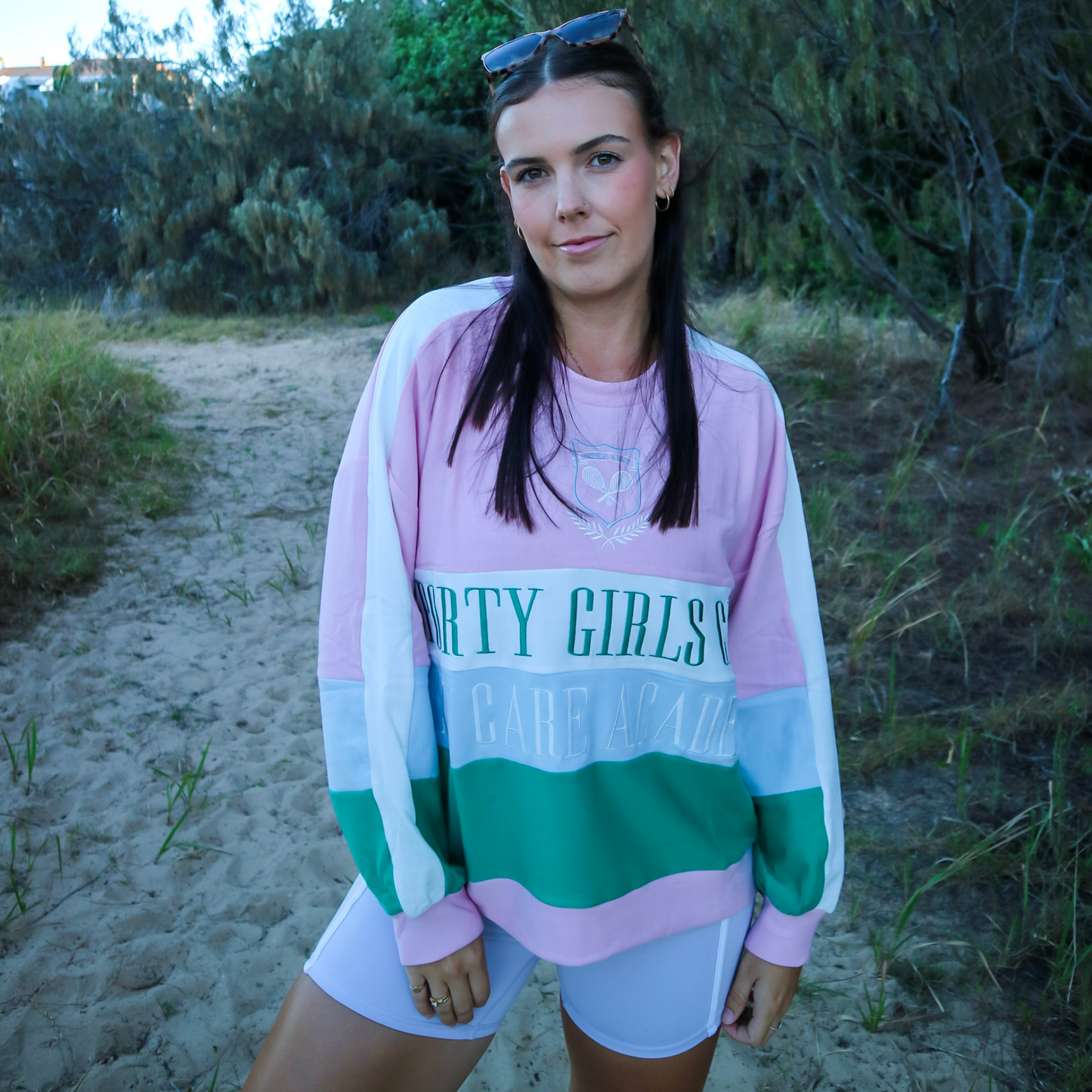 Woman wearing a colorful sweatshirt with text on a sandy path
