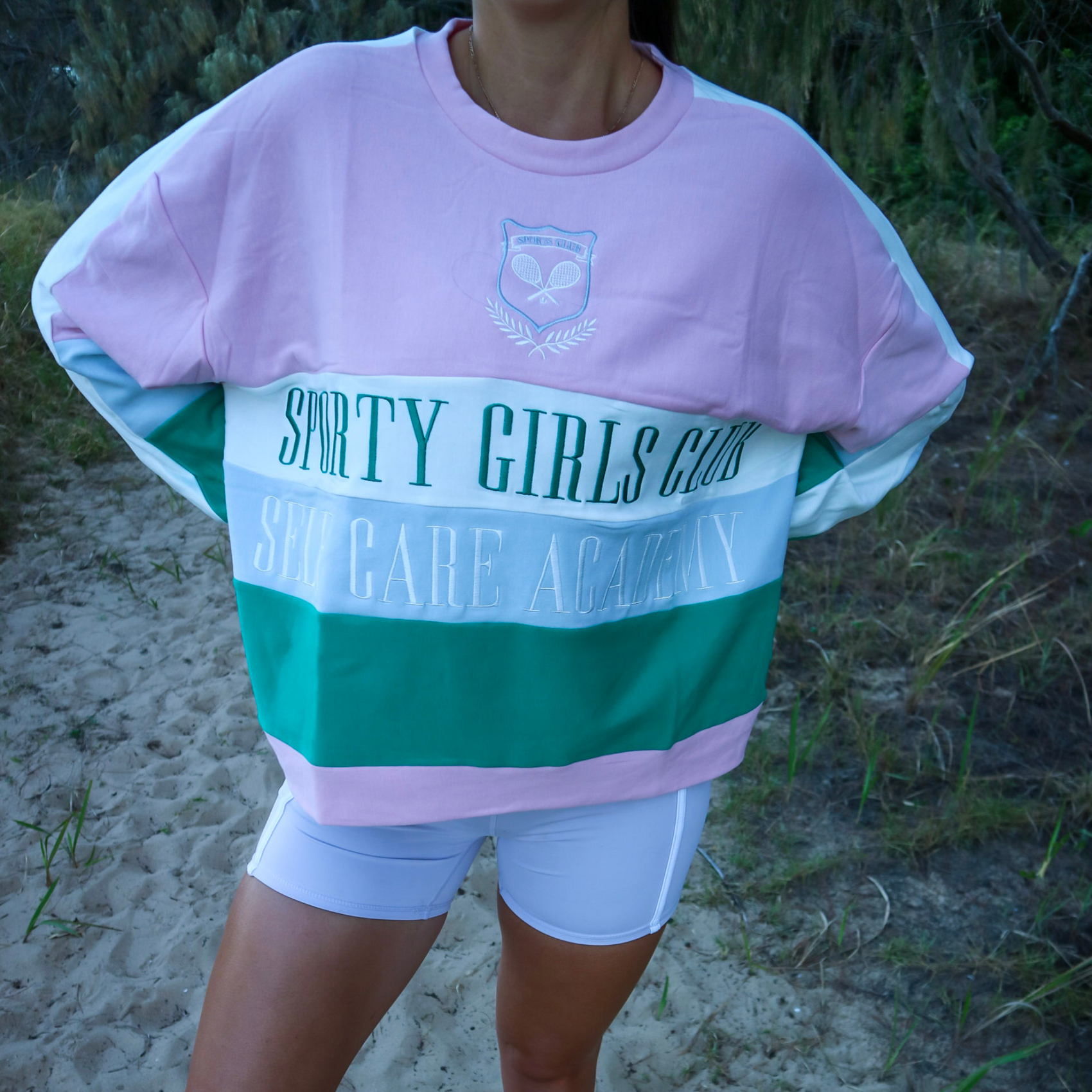 Person wearing a colorful sweatshirt with 'Sporty Girls Club' text in an outdoor setting