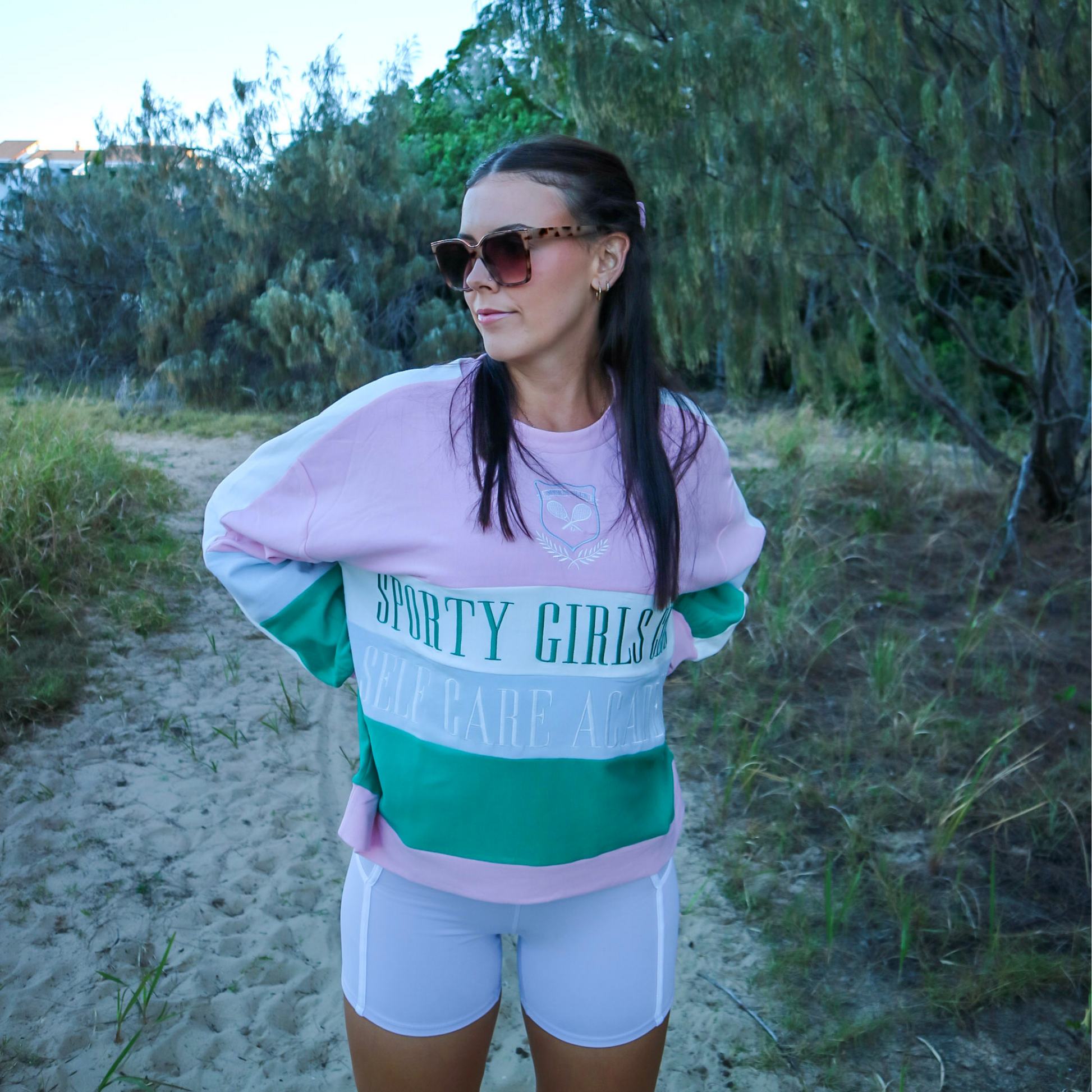 Woman wearing a 'Sporty Girl' sweatshirt on a beach path