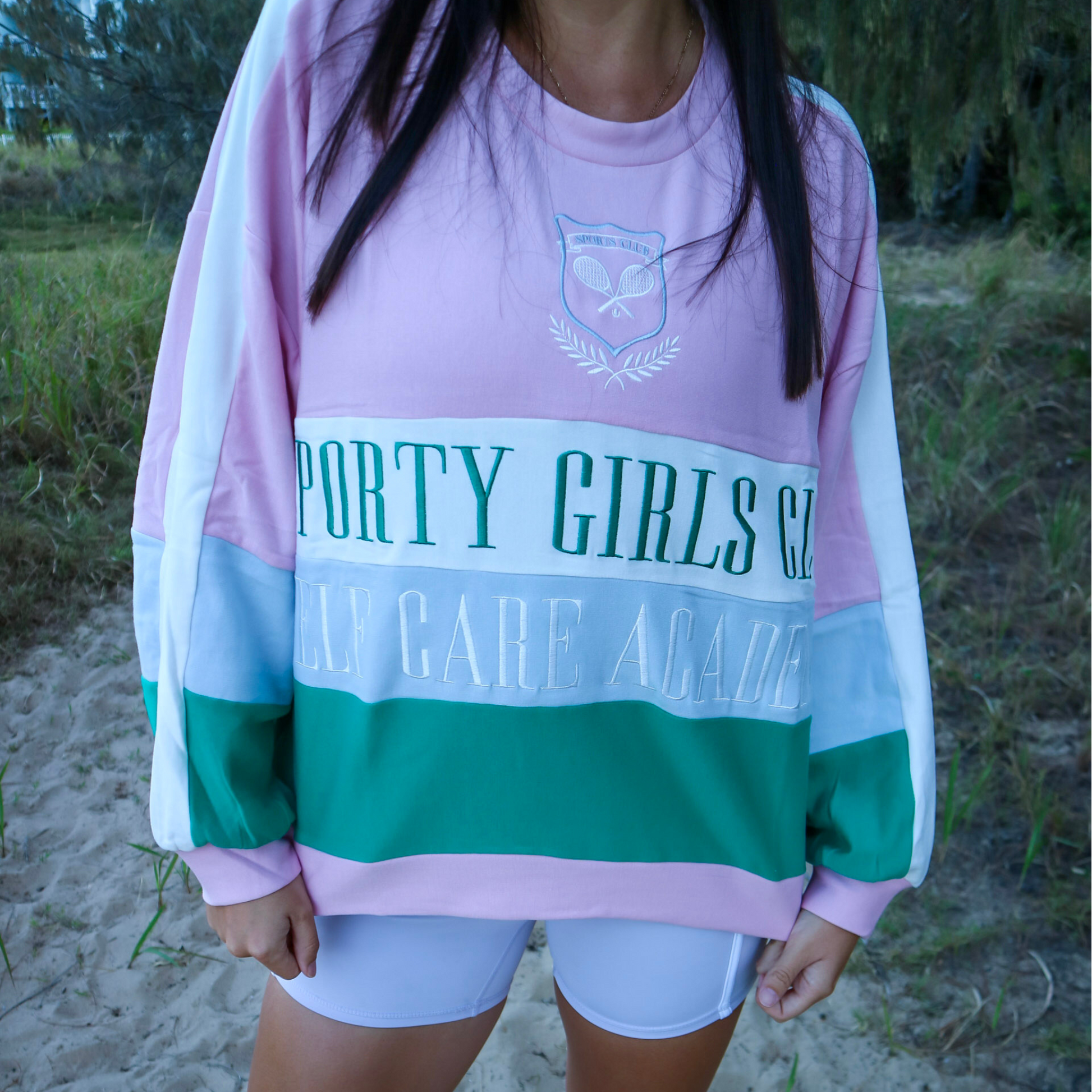 Person wearing a colorful sweatshirt with text on a beach
