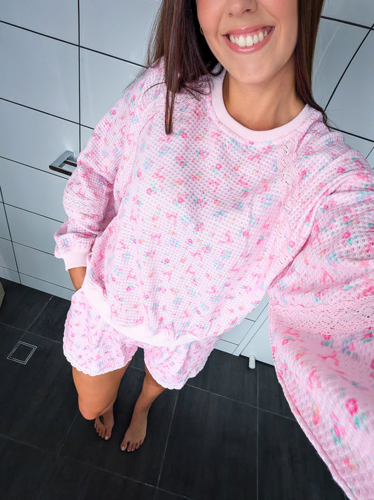 Person wearing a pink floral loungewear set in a bathroom.