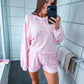 Woman taking a mirror selfie wearing a pink loungewear set in a bathroom.