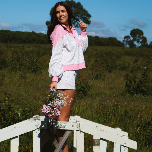 Model wearing a two-piece loungewear set featuring a cozy jumper and matching shorts with floral detailing and soft pink accents, perfect for relaxed comfort with a feminine touch.